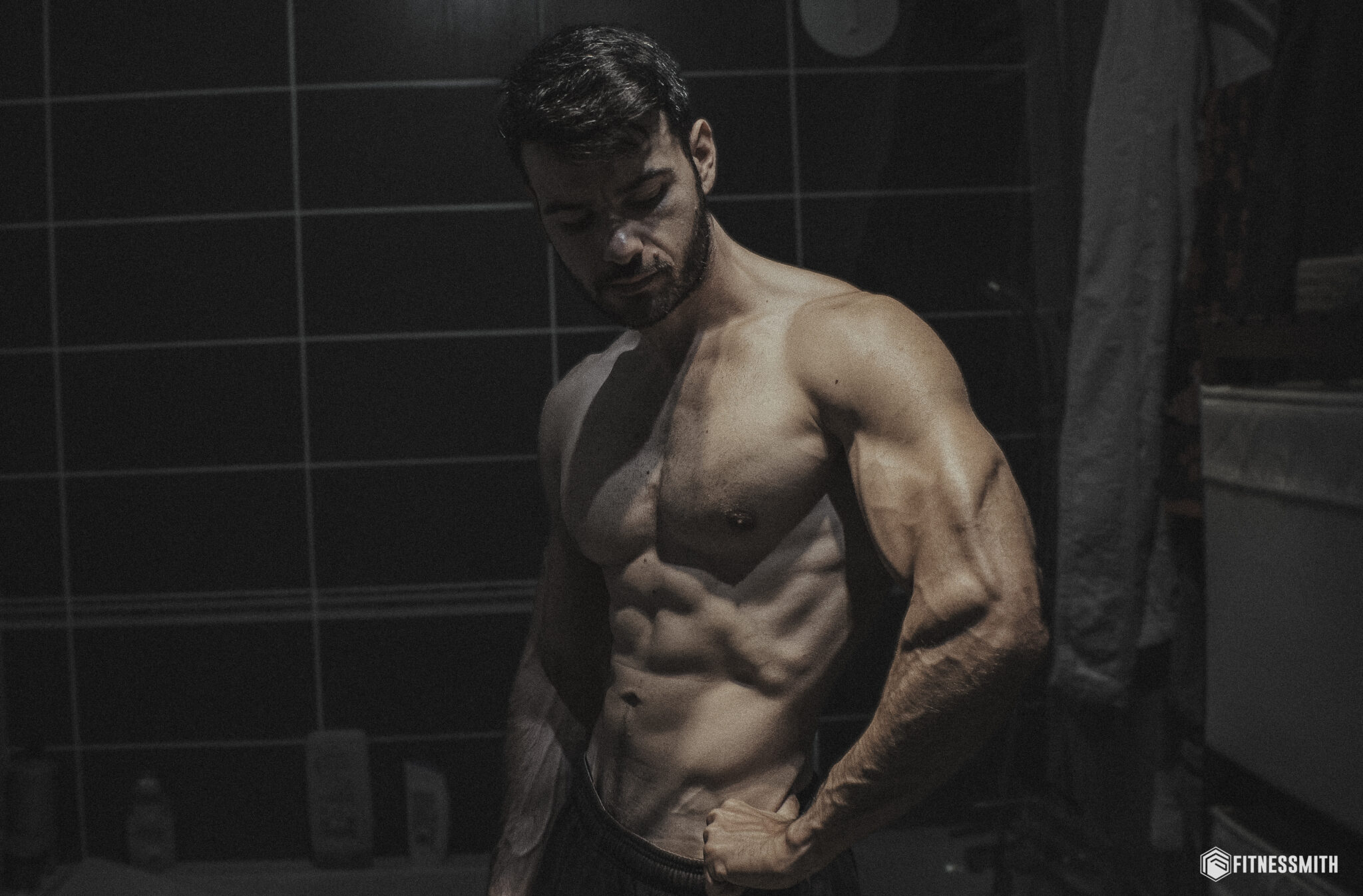 Homme musclé au physique naturel montrant des abdominaux définis sans dopage, dans une salle de bain