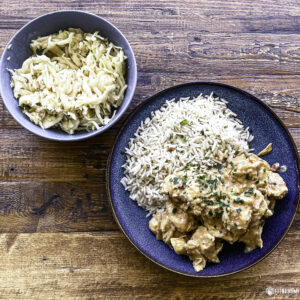 Assiette de poulet au beurre de cacahuète, riz semi-complet et salade de chou sur table en bois
