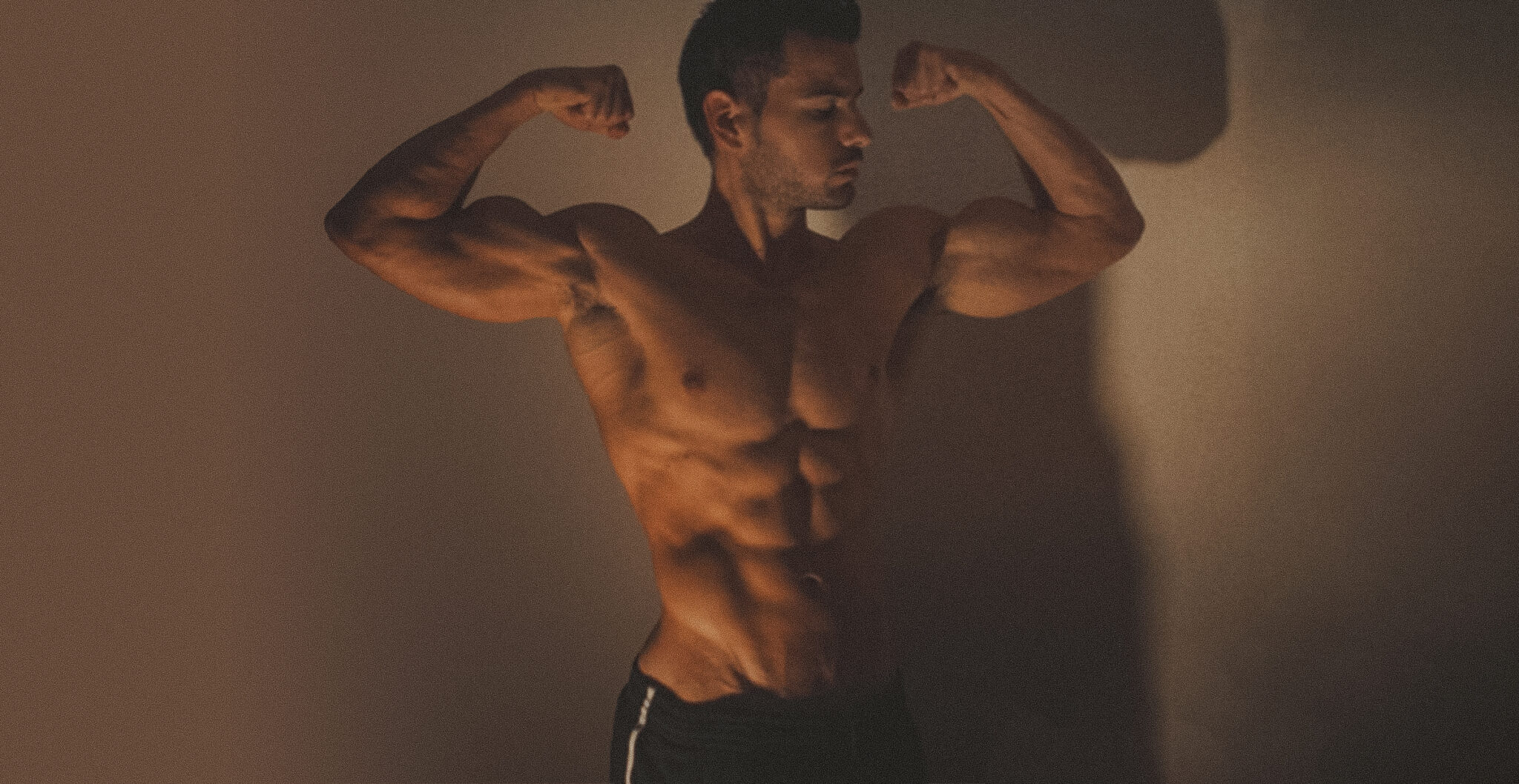 Athlète torse nu flexant les biceps pour progresser en musculation et vaincre l’inconfort