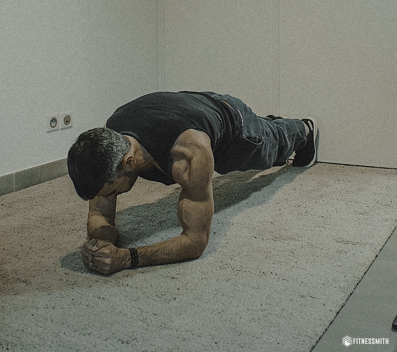 Exercice de gainage pour renforcer les abdominaux, démontré par un homme musclé au sol en position planche