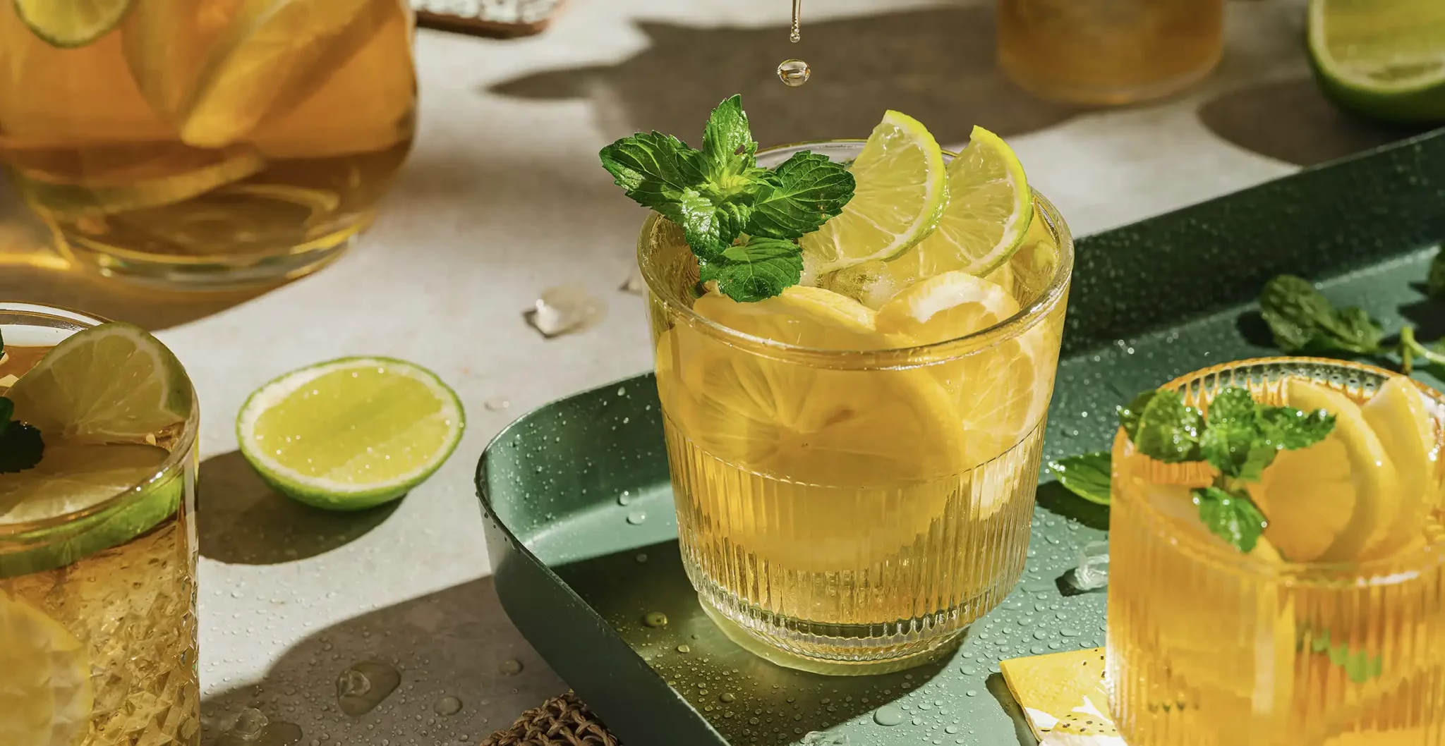 Verres de thé glacé brûle-graisse au citron, gingembre et menthe sur fond lumineux